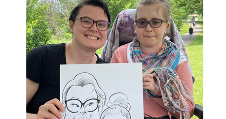 A teenage student and her intervener are holding up a caricature artist drawing of themselves