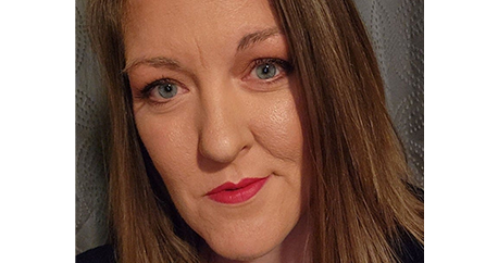 Close up picture of Michele's face. White cis-gender middle-aged woman with blue eyes, brown shoulder-length straight hair, and a black shirt